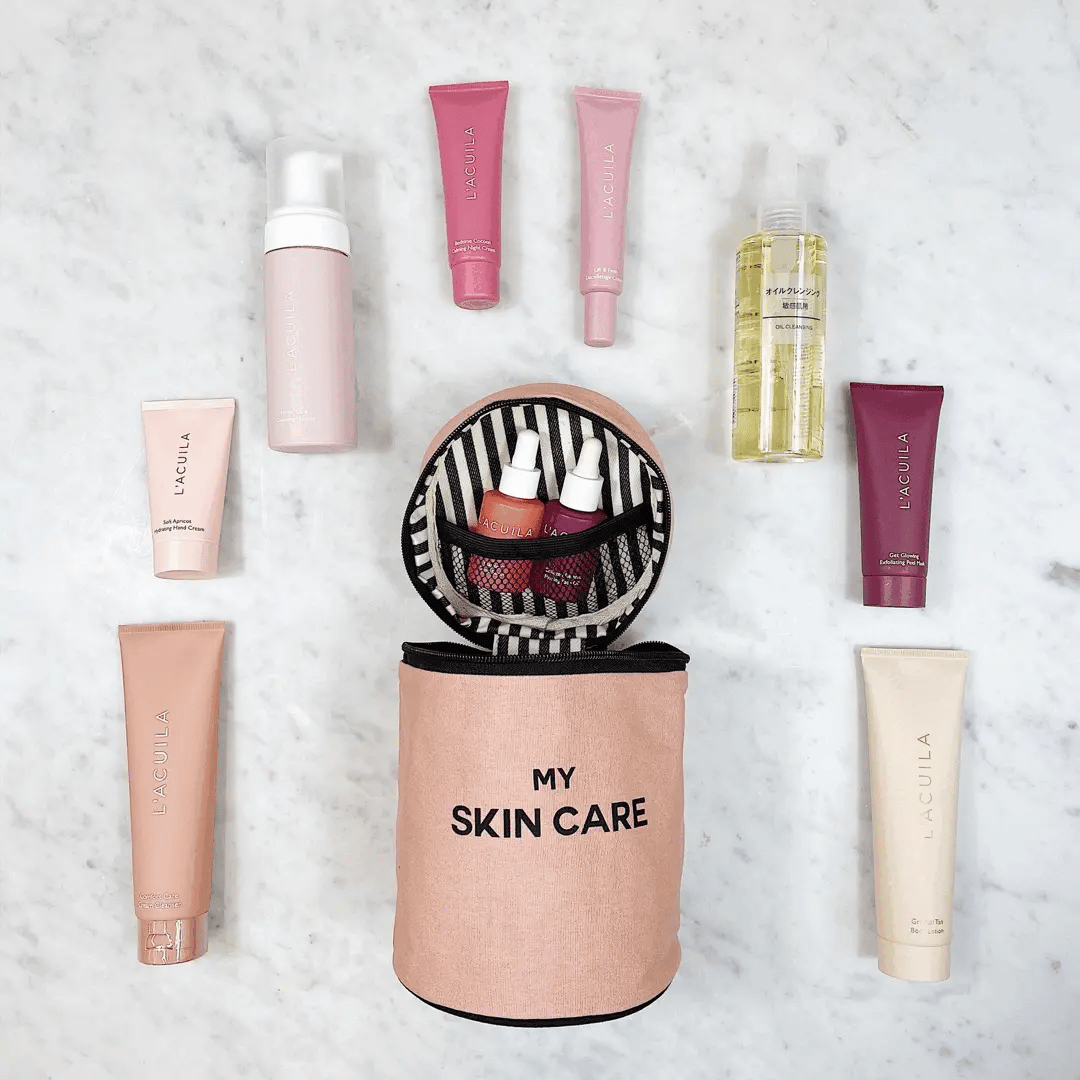 Bag-all Round Skin Care Case with Handle in Pink displaying organized beauty products, featuring striped interior lining and 'My Skin Care' text on blush pink cylindrical container on marble surface
