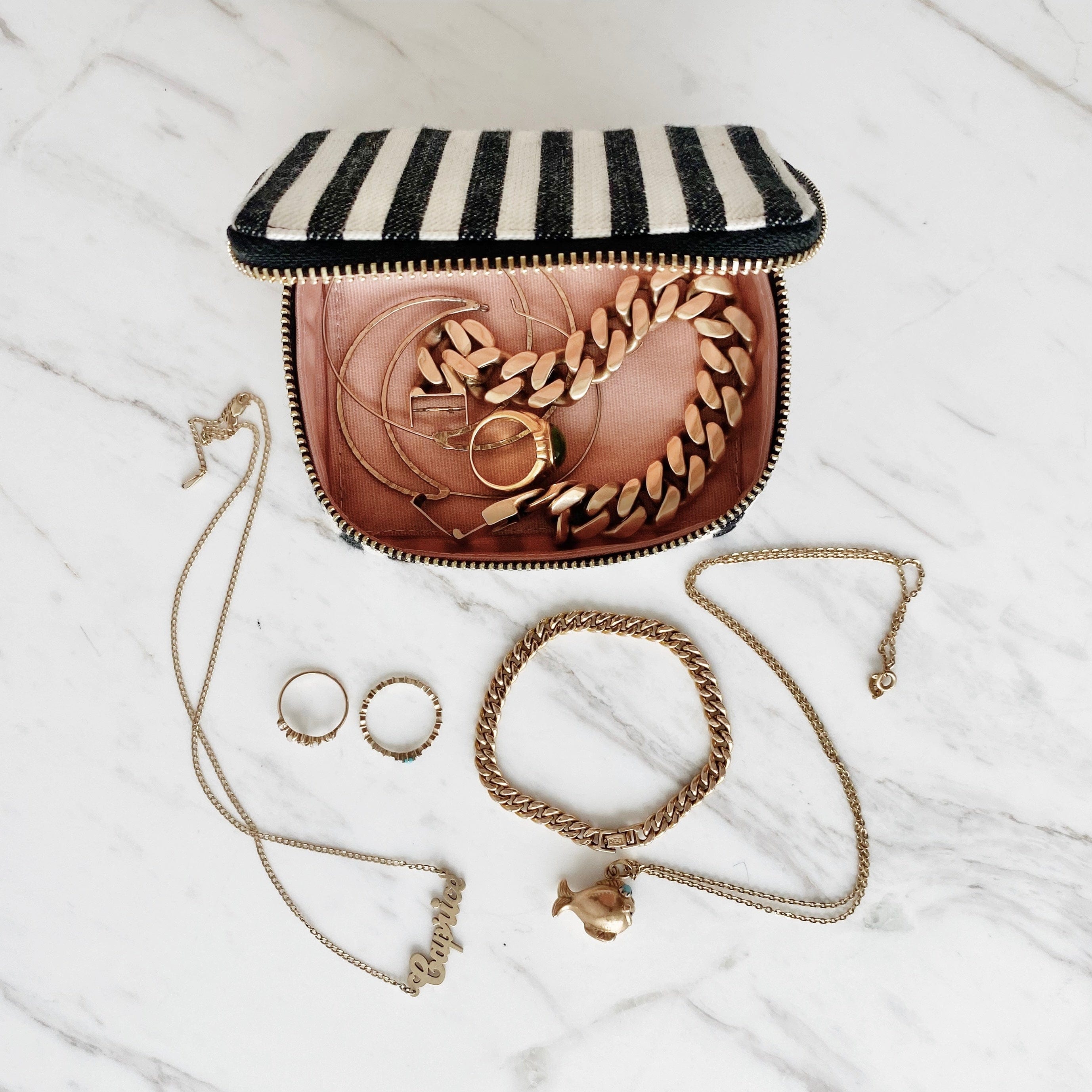 Bag-all Handbag Organizer Trio featuring striped cotton makeup pouch, jewelry box and earbud case with gold jewelry accessories displayed on marble surface