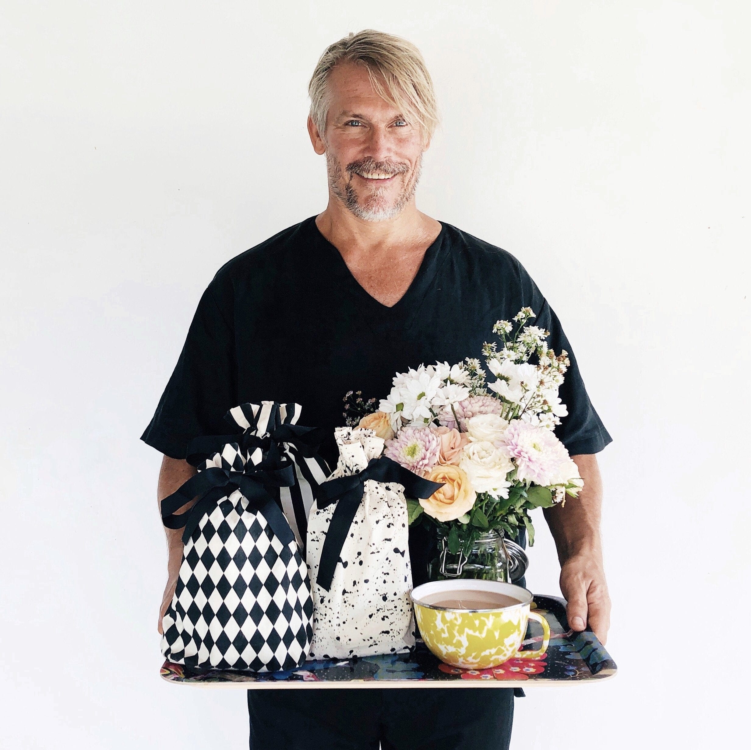 A tray with coffee, flowers and patterned reusable gift bags. 