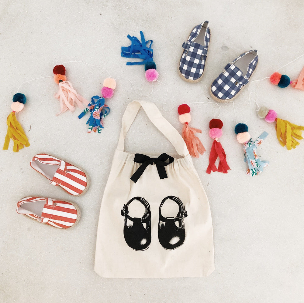 
                                      
                                        Baby shoes surrounding a white organizing bag that has a picture of baby shoes printed on the front. 
                                      
                                    