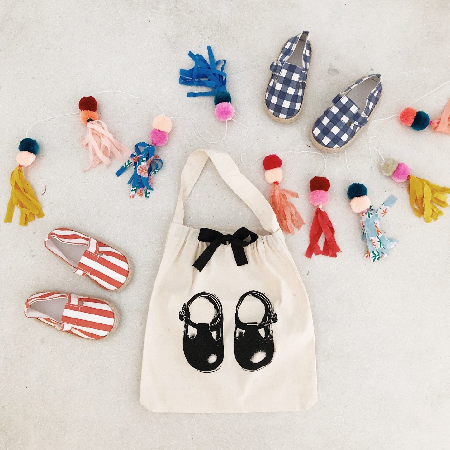 Baby shoes surrounding a white organizing bag that has a picture of baby shoes printed on the front. 