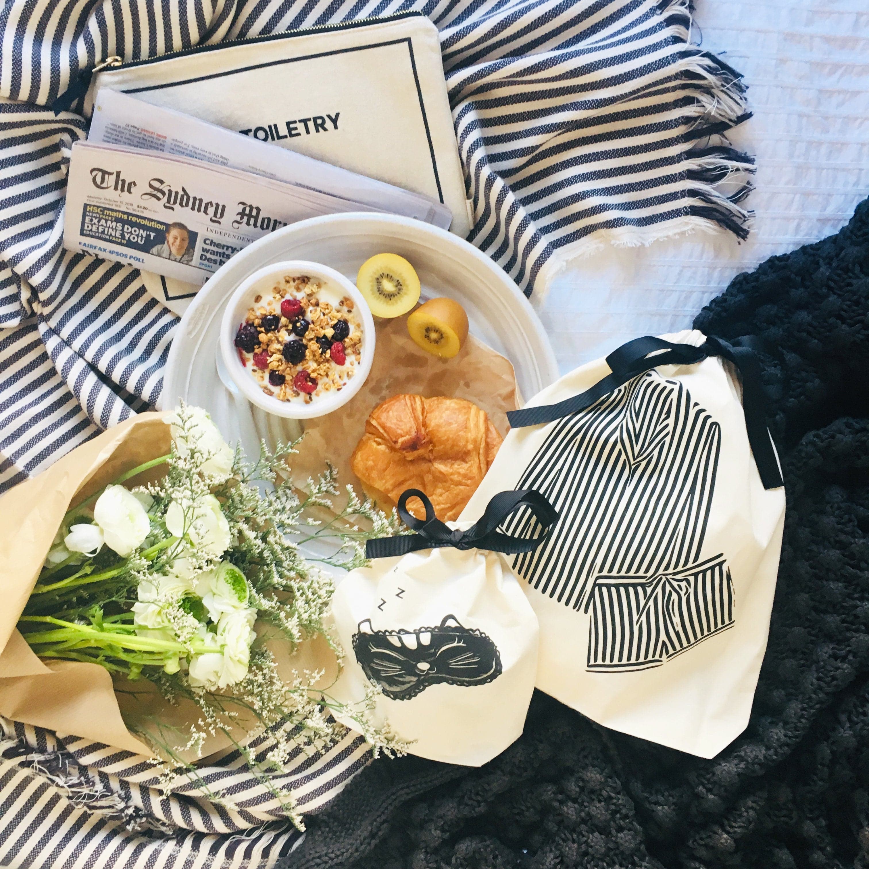 A morning breakfast, flowers, striped pajamas bag and a sleepy cat mask bag. 