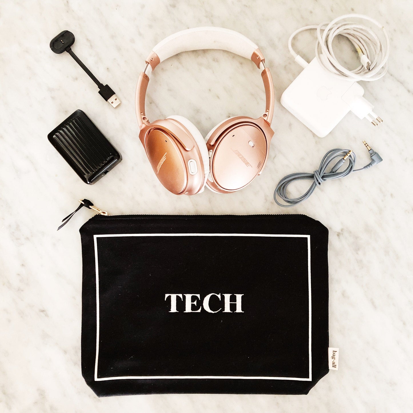 Bag-all Tech Pouch in black canvas with white border featuring rose gold headphones, charger, and cables - stylish organizer for electronics and gadgets