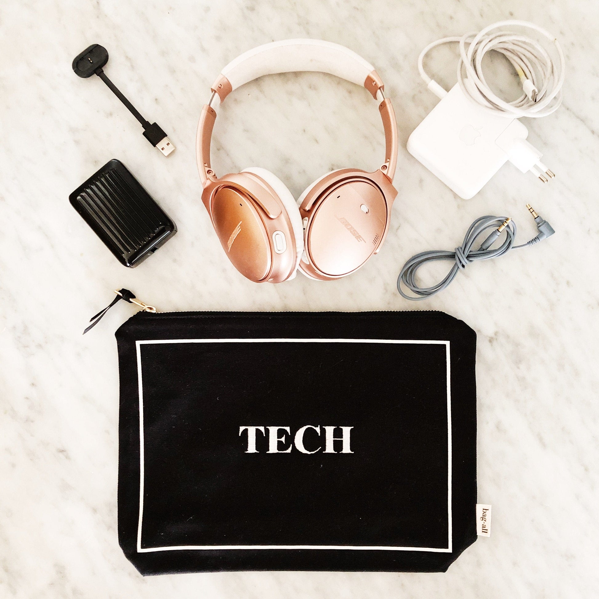 Bag-all Tech Pouch in black canvas with white border featuring rose gold headphones, charger, and cables - stylish organizer for electronics and gadgets
