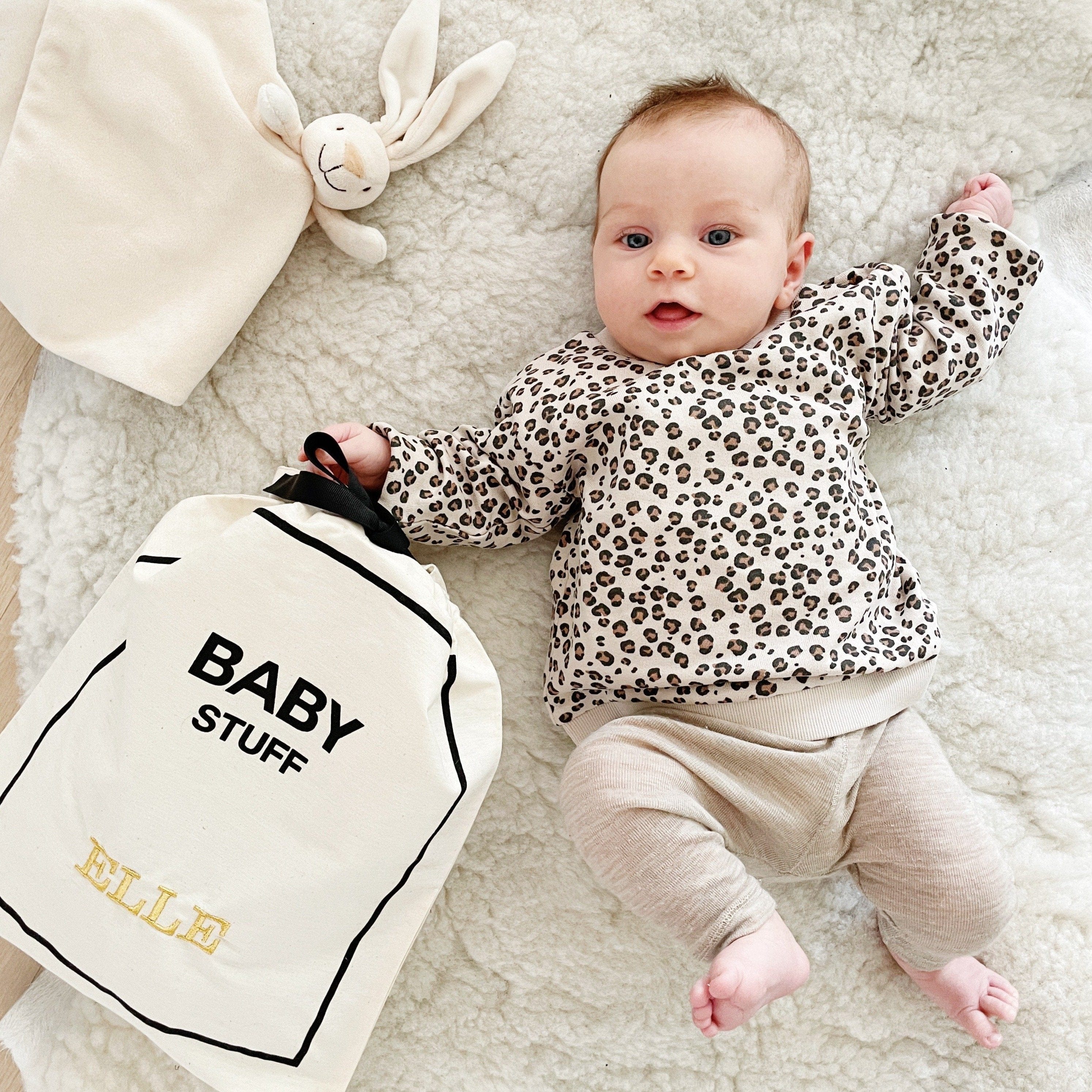 Baby laying on a bed with baby bag organizing bag. 