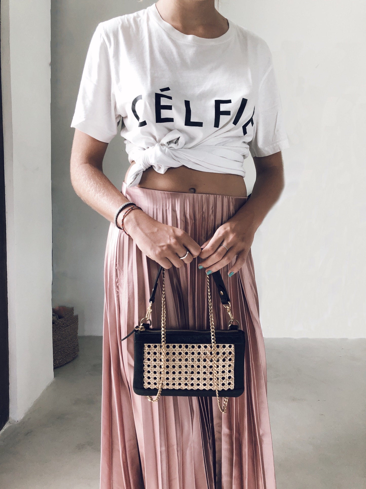 
                                      
                                        A girl holding a rattan bag with a leather strap and a gold chain. 
                                      
                                    