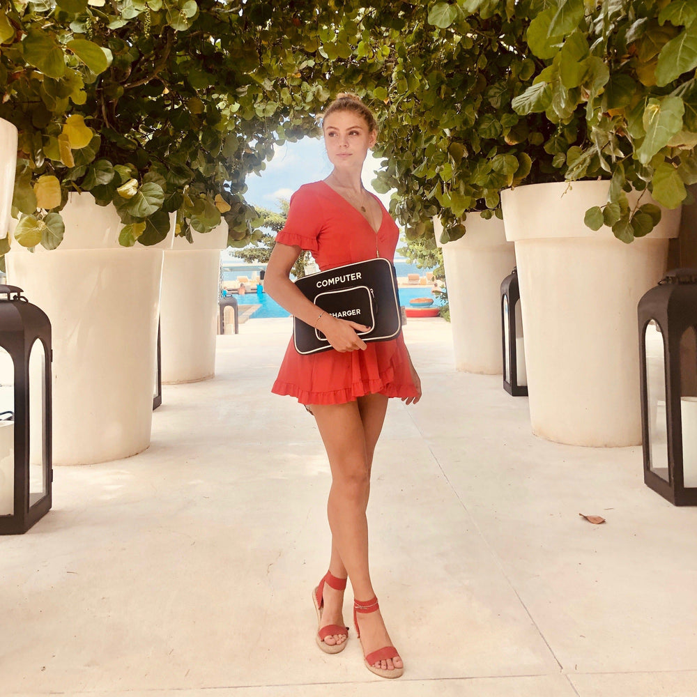 A girl in a red dress holding a black laptop sleeve case.
