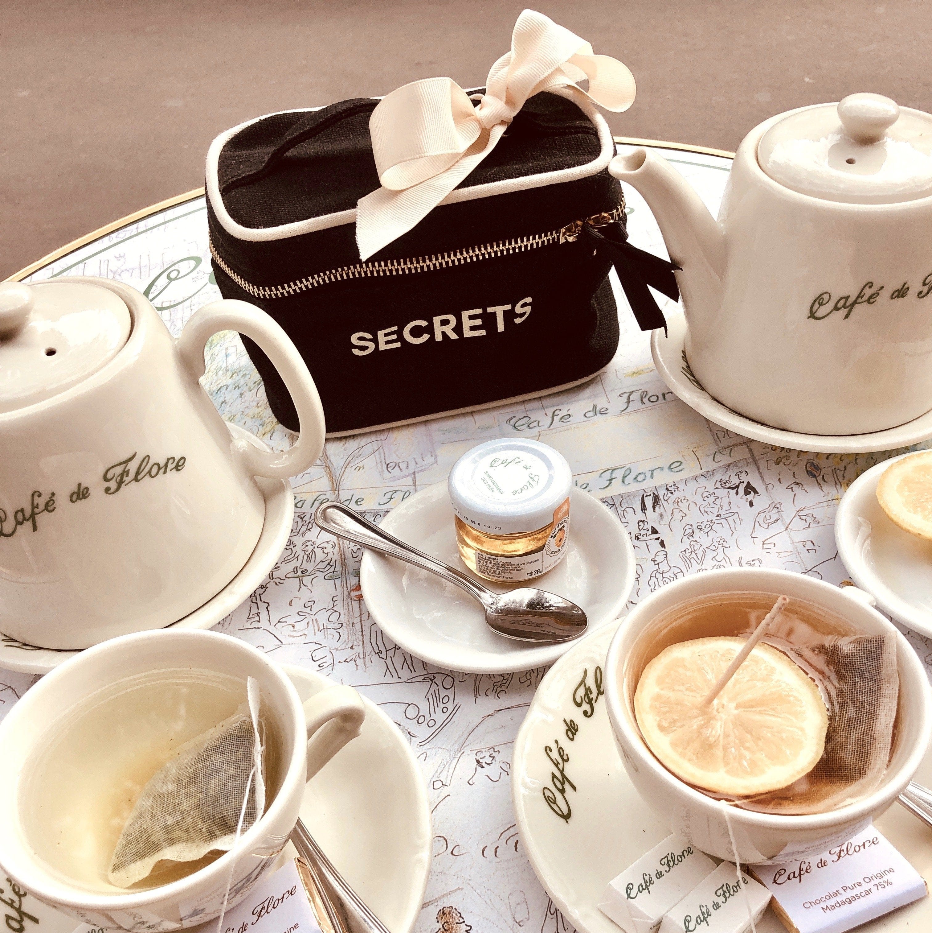 A coffee shop table with coffee and tea with a mini secrets beauty box on the table. 