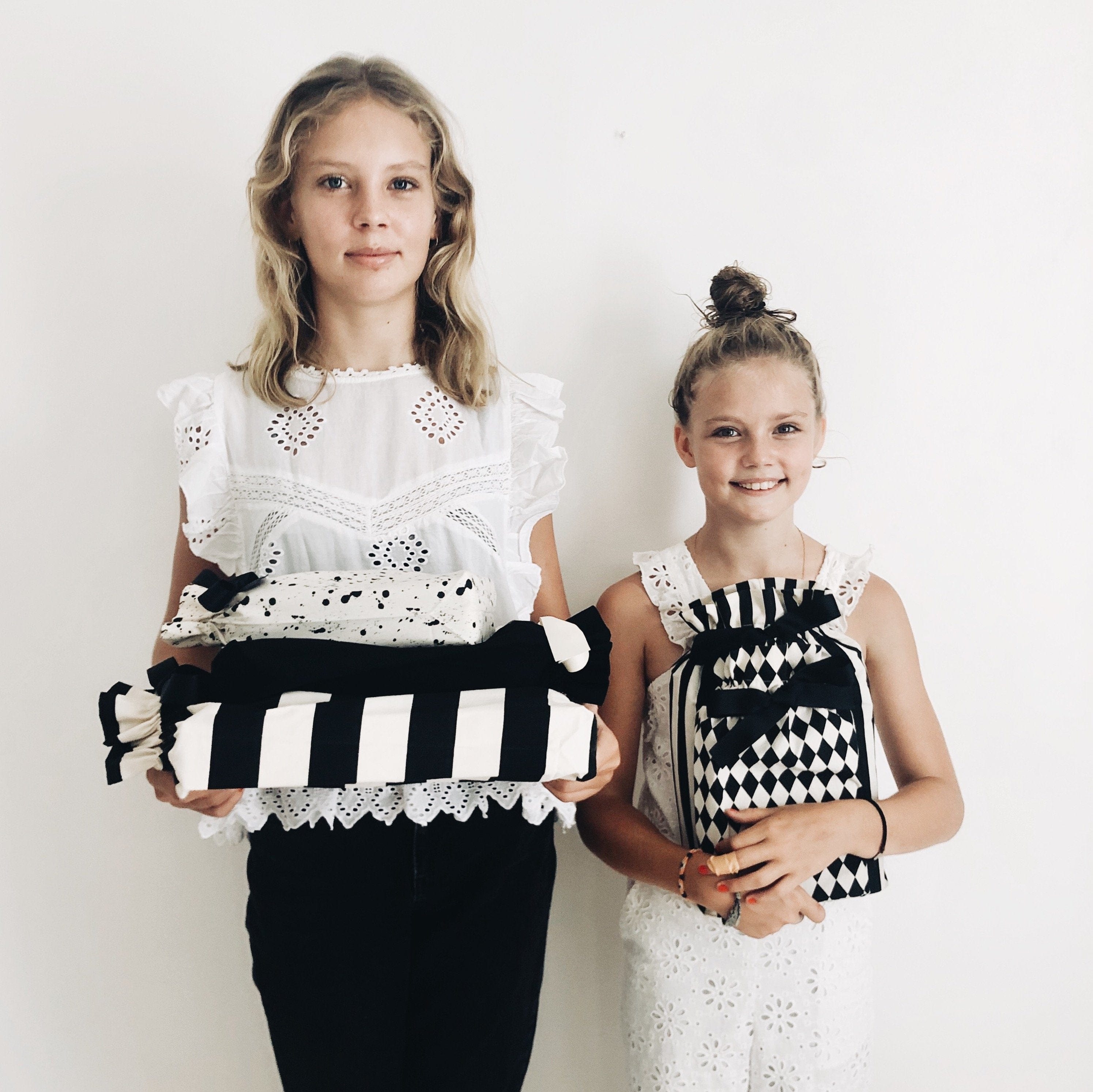 Two girls holding reusable gift bags in different patterns. 