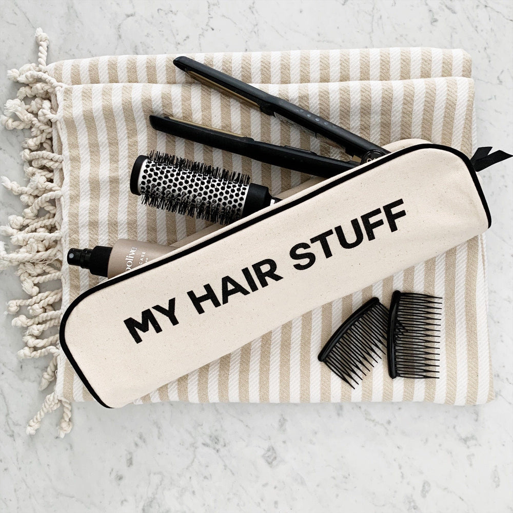 
                                      
                                        A rounded brush, hair straightener, comb and hair product in a hair stuff case. 
                                      
                                    