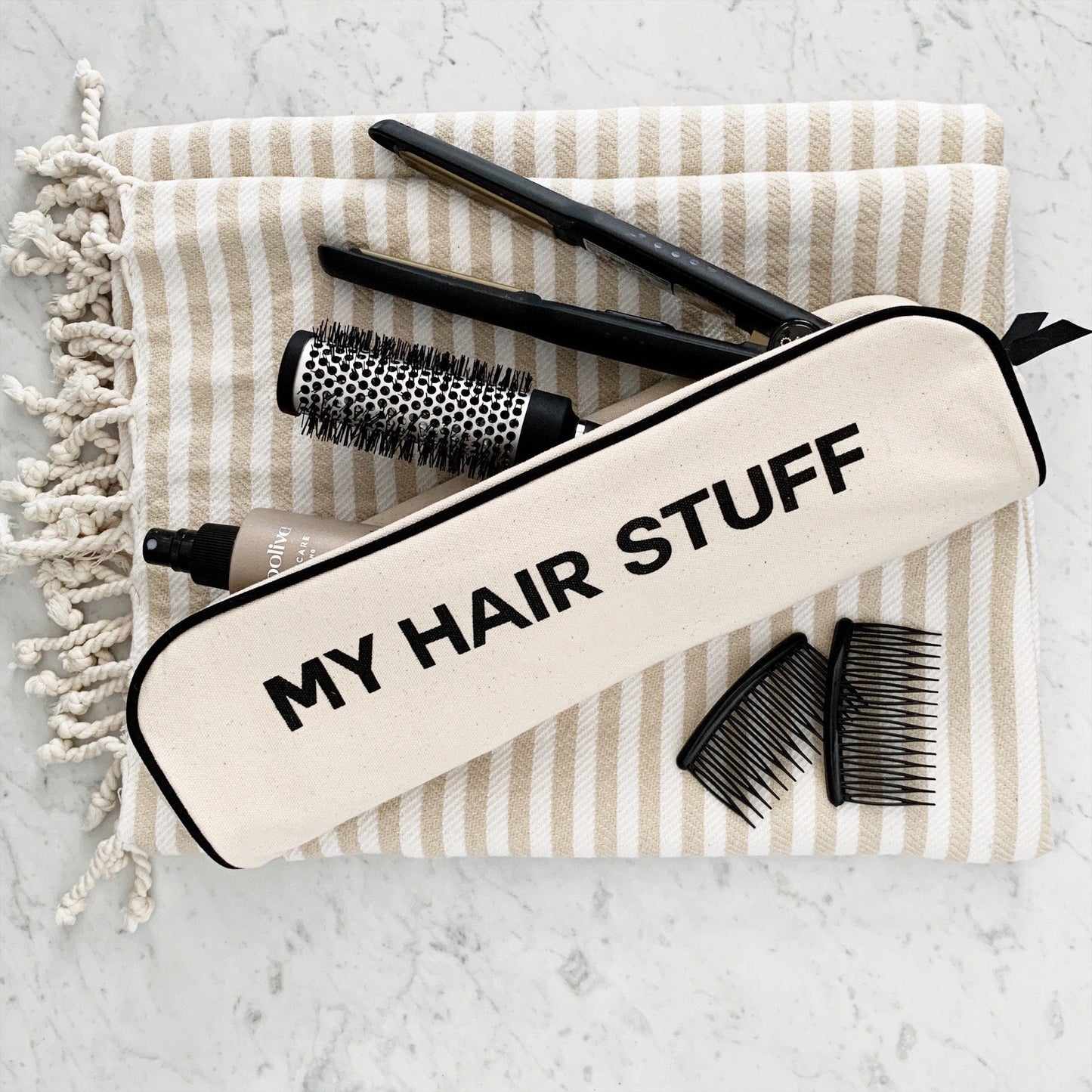 
                                      
                                        A rounded brush, hair straightener, comb and hair product in a hair stuff case. 
                                      
                                    