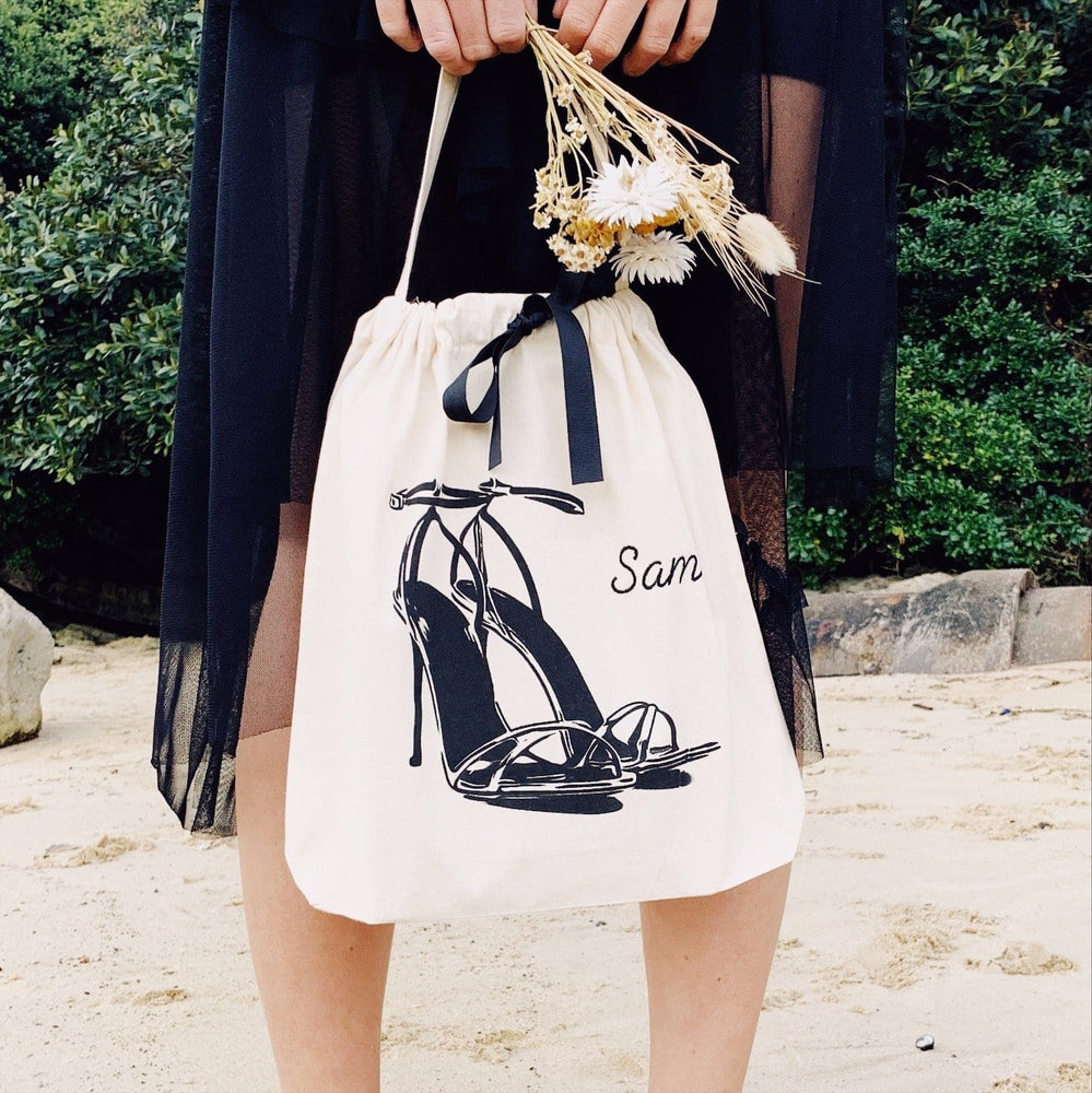 
                                      
                                        A girl in a black dress holding flowers and high heel sandals.
                                      
                                    