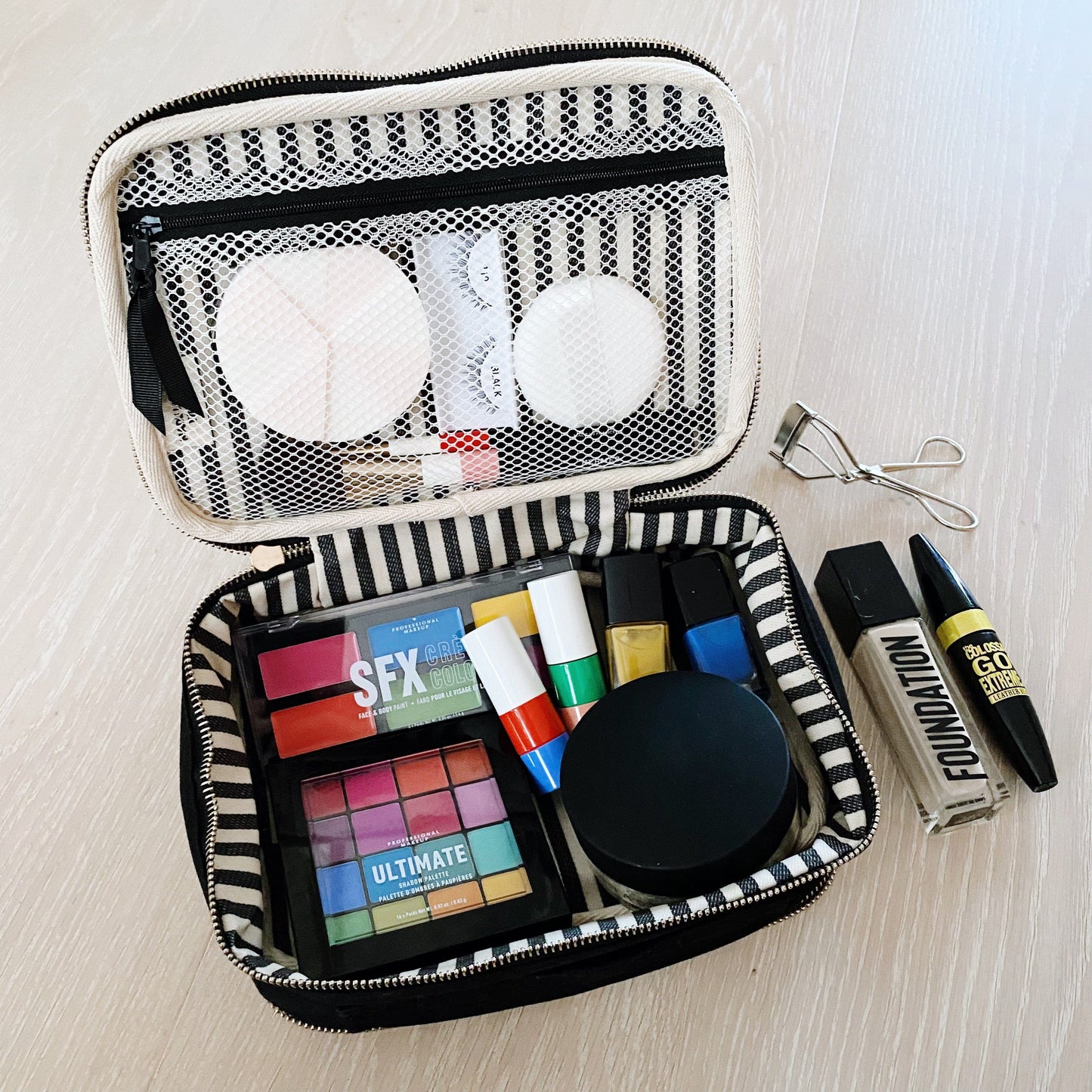 Bag-all Double Sided Toiletry Case in Black featuring waterproof interior, dual compartments with elastic straps, shown open displaying makeup and beauty products with striped lining and mesh organization panel
