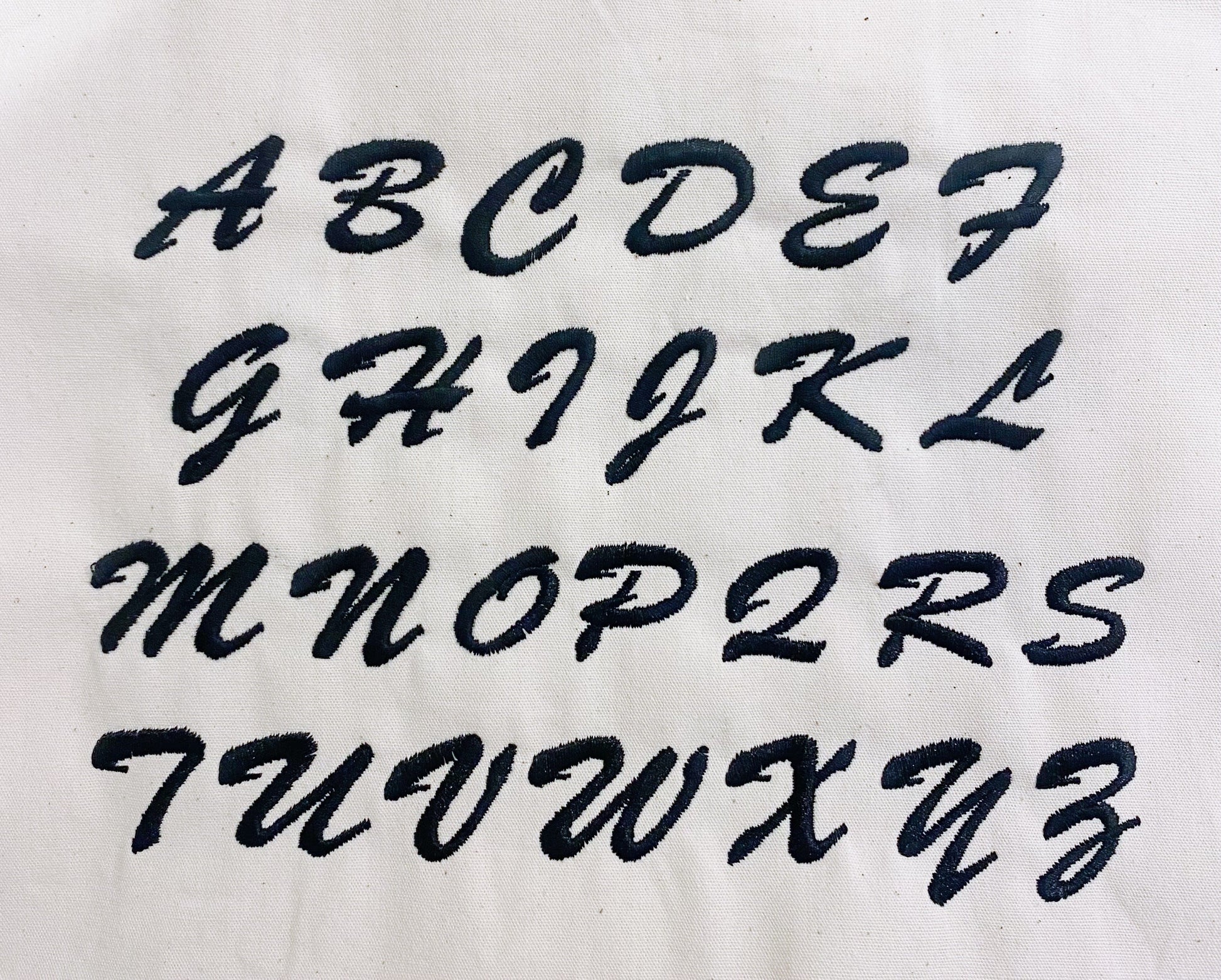 Bag-all monogram font alphabet displayed in cursive style for personalized bag customization. Letters A to Z shown in elegant black script for custom monogramming options.