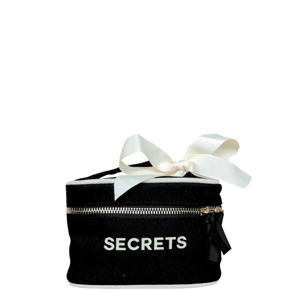 Mini black beauty box with "secrets" across the front and a white bow on the handle. 
