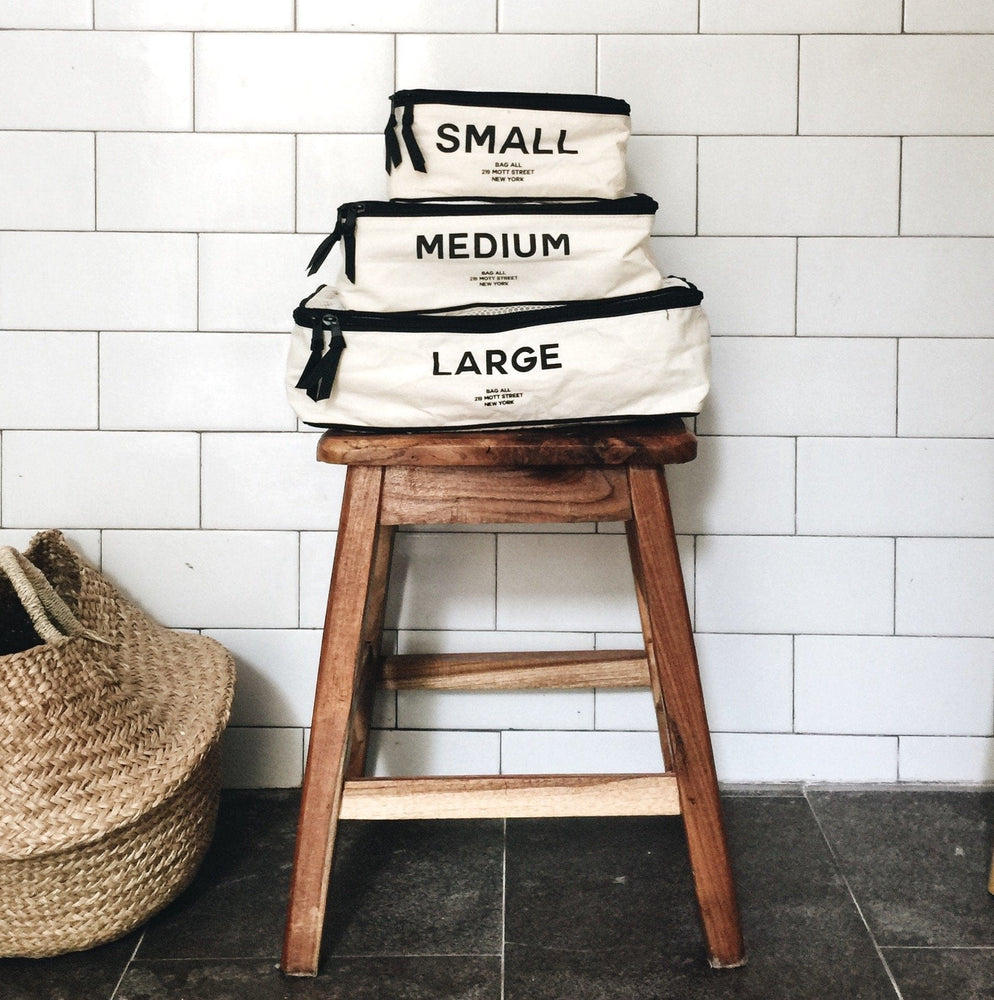 
                                      
                                        A wooden stool with three packing cubes labeled "small", "medium" and "large".
                                      
                                    