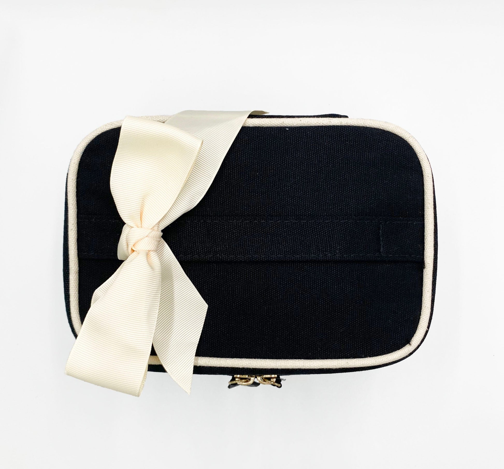 Bag-all Vitamins Storage and Travel Box in black canvas with cream ribbon bow, featuring contrast piping and zipper closure, perfect for organizing supplements