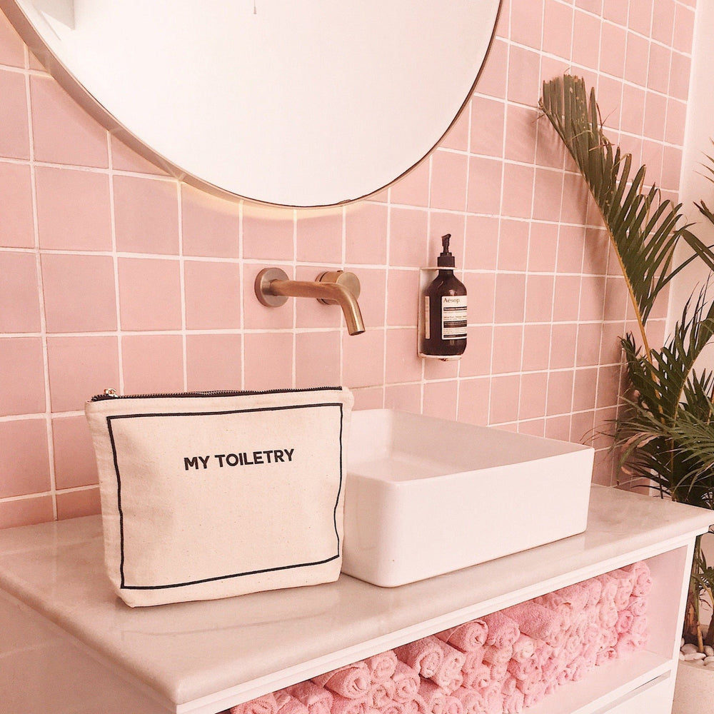 
                                      
                                        A light pink bathroom and a toiletry case on the counter top. 
                                      
                                    